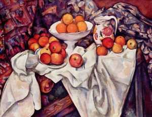 A still life painting of oranges and apples on a white cloth; some are on a plate and others scatter on the table near a floral-patterned jug. The background features draped, multicoloured fabric with painterly, textured brushstrokes.