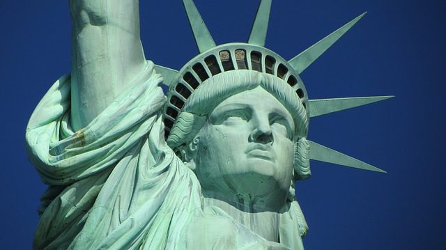 Close-up view of the Statue of Liberty’s face and torch-lit arm in New York, with her iconic green copper exterior against a deep blue sky—an unforgettable sight near many cozy Bed & Breakfast options for travelers.