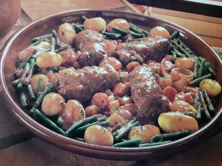 A rustic brown dish featuring Paupiettes de Boeuf: four pieces of braised meat, small round potatoes, green beans, and sliced carrots, all coated in a glossy brown sauce and garnished with herbs for a classic French beef recipe.